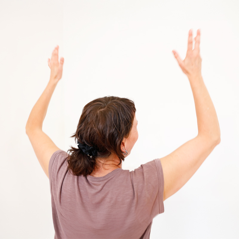 Ansicht von hinten; Oberkörper einer Frau mit erhobenen Händen beim Tanzen