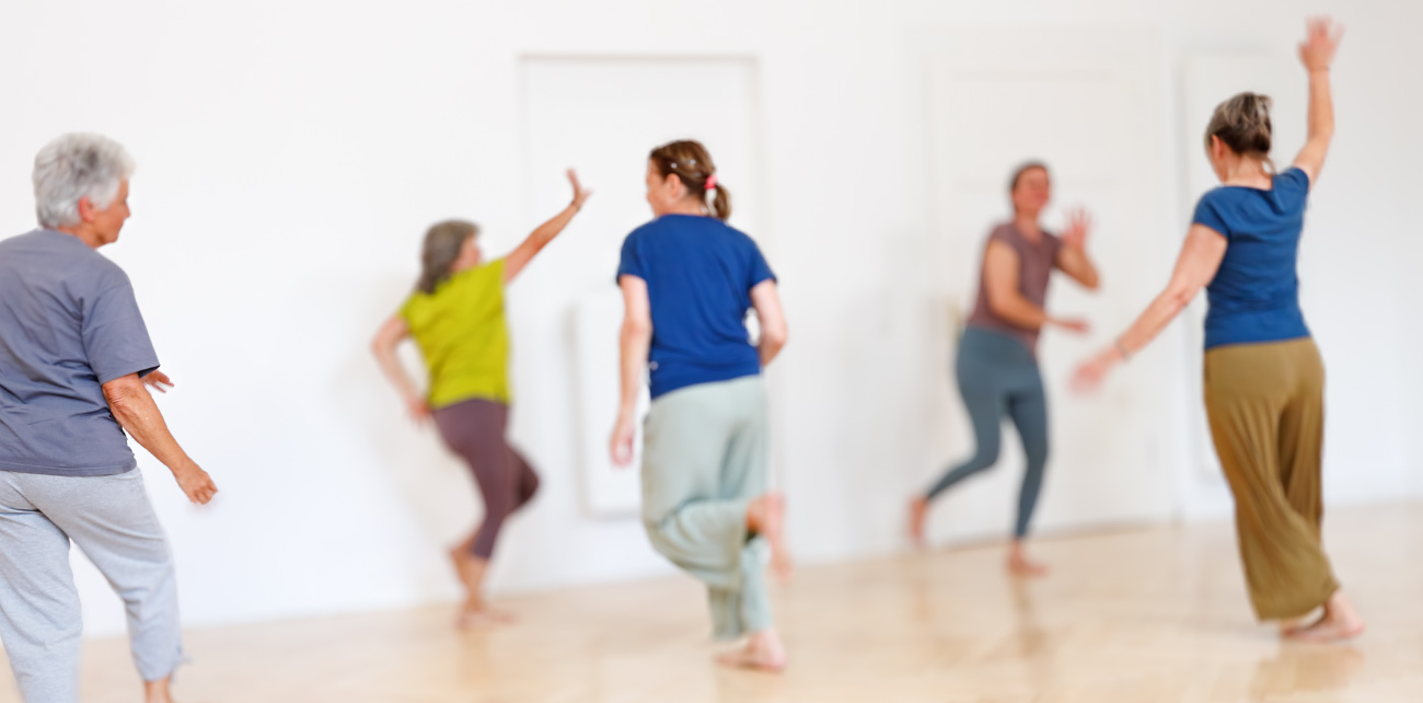 Fünf Frauen in Sportkleidung tanzen frei durch einen hellen Raum